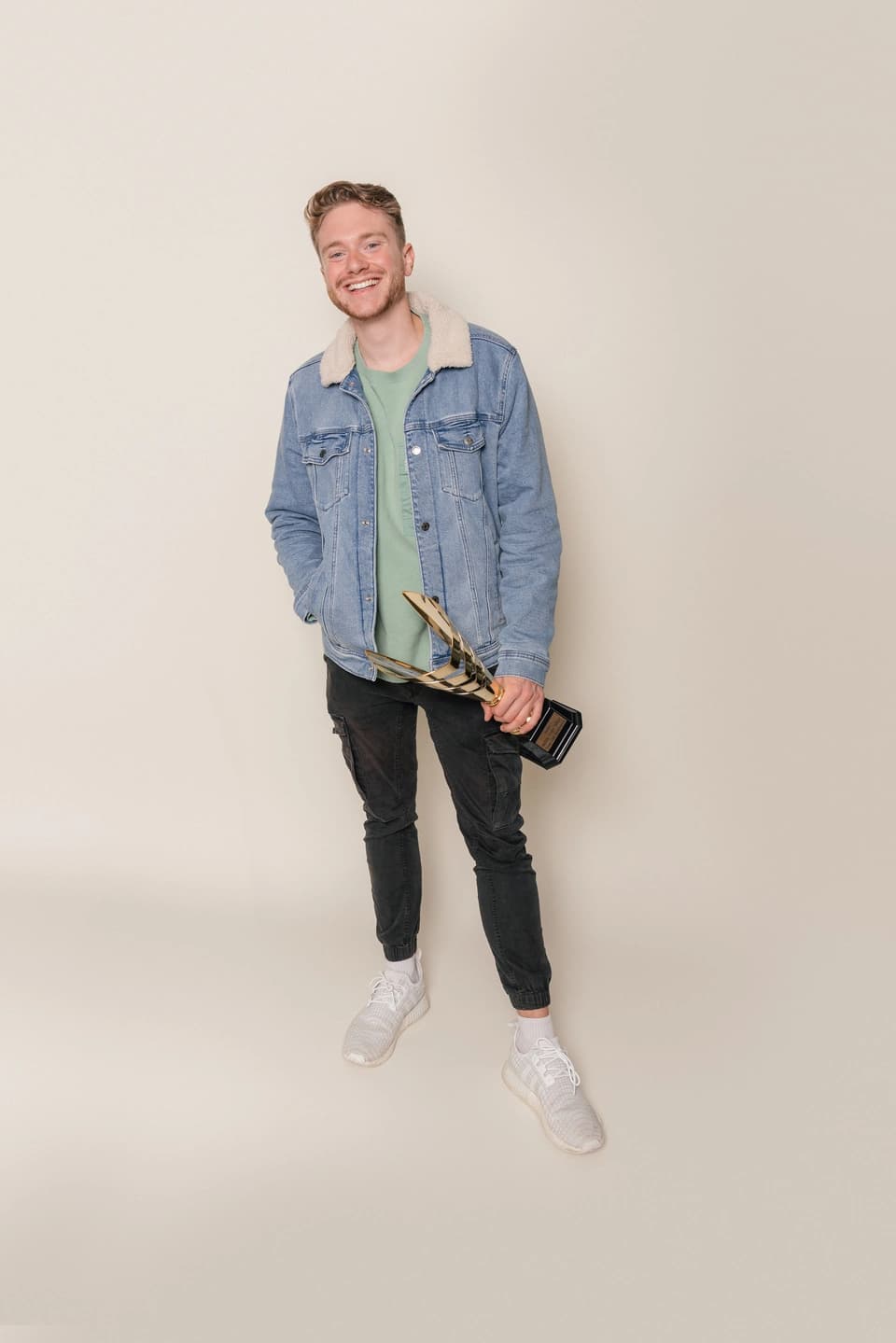 A person smiling at the camera holding a trophy